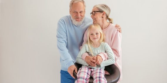 Smiling grandparents with grandchild, embracing intergenerational love.